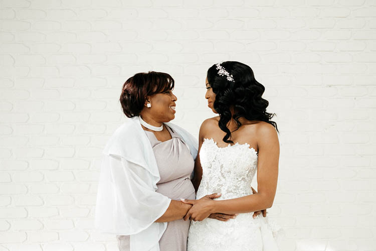 Bride & Mom in Front of White Brick Wall Before Wedding | photo by The Portos